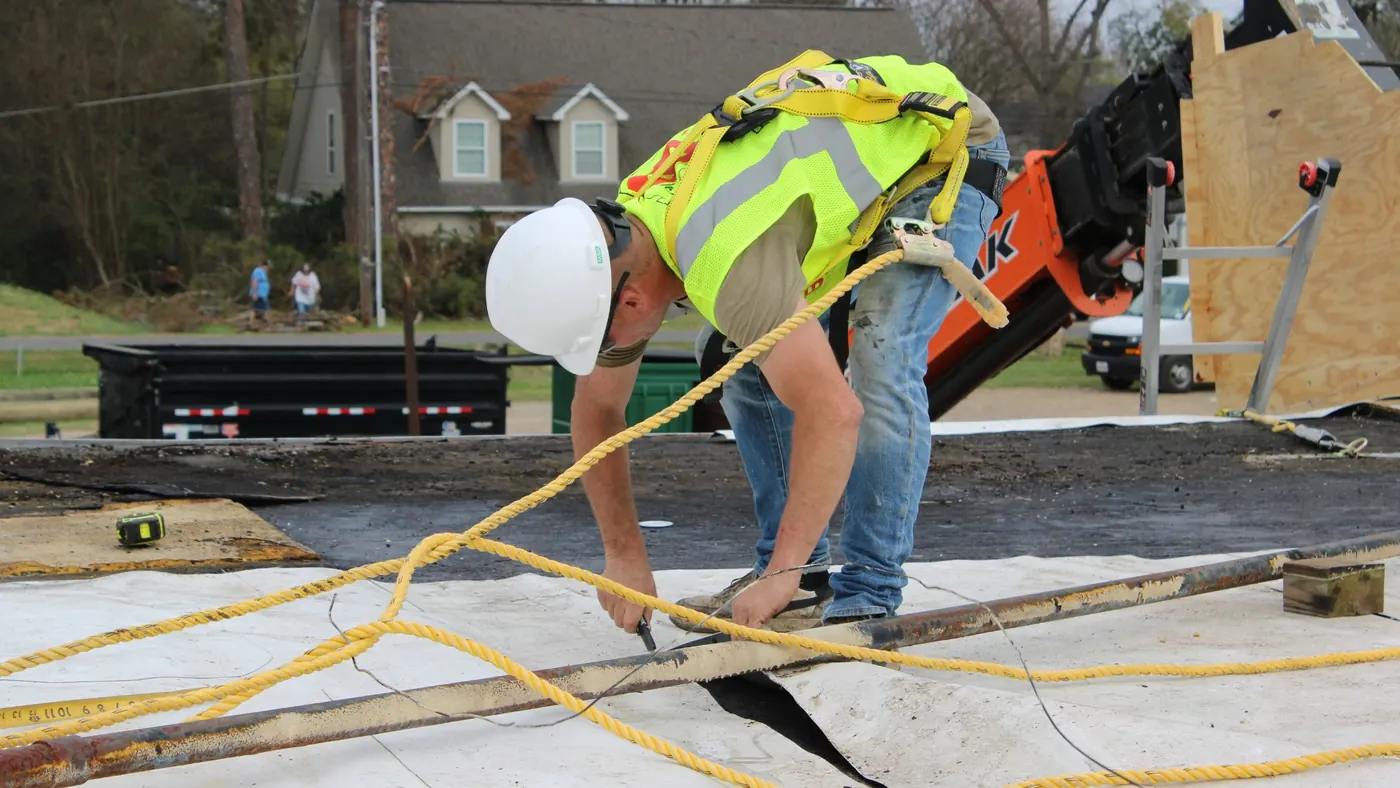 Brown's Roofing crew member working a modified bitumen seam on a commercial flat roof with telehandler in background