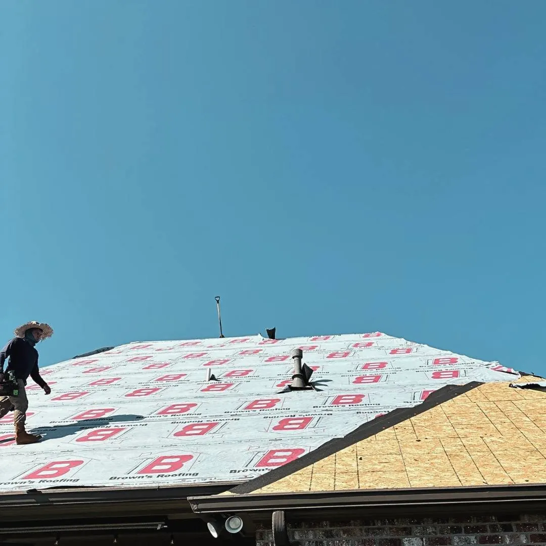 Brown's Roofing crew member walking across a residential roof covered in Brown's branded synthetic underlayment