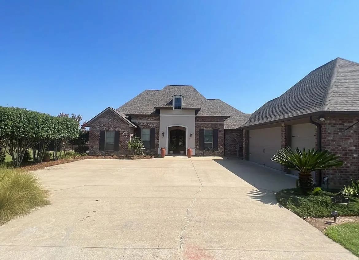 Acadian-style brick home with new shingle roof and three dormers