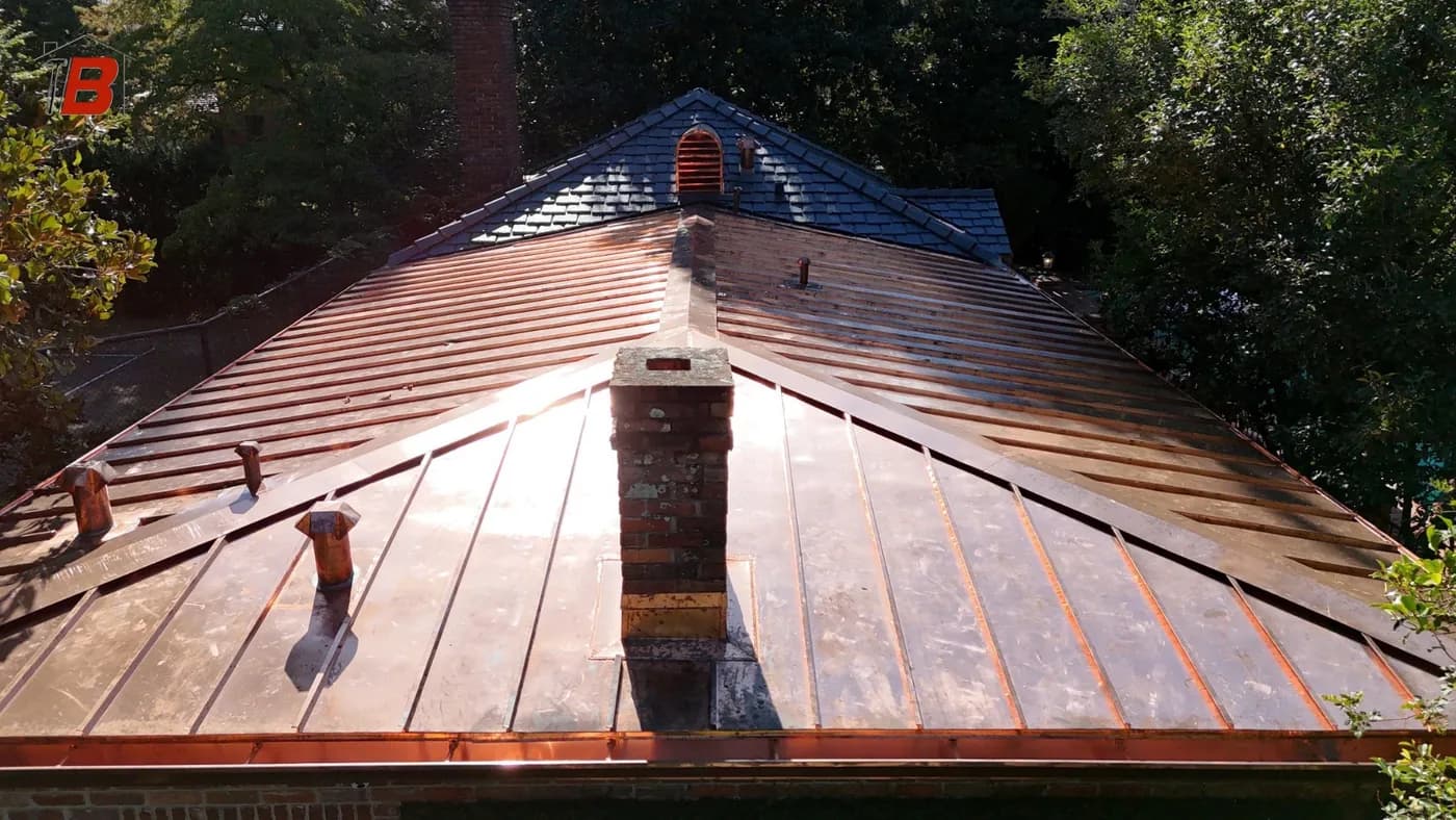 Copper standing-seam metal roof installation with brick chimney detail