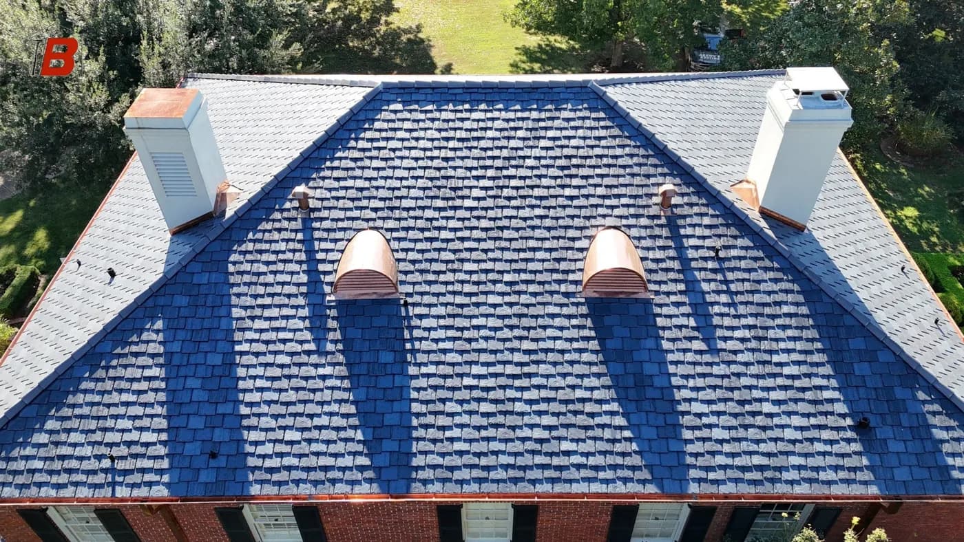 Drone aerial of a synthetic slate roof in blue-gray tones with copper dormer caps