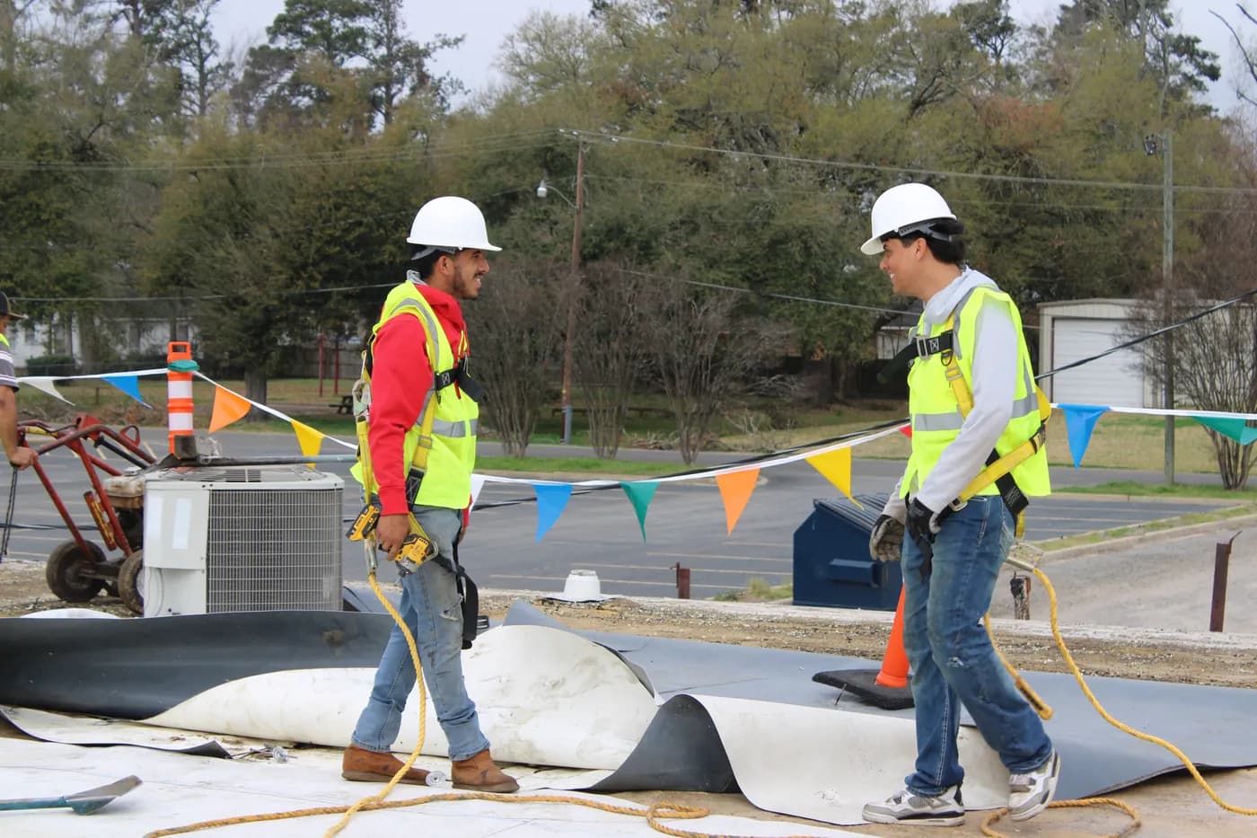 Two Brown's Roofing crew members in hard hats on a commercial flat roof with HVAC units behind them