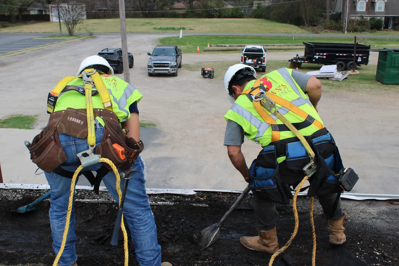 Brown's Roofing crew shoveling tear-off material at the edge of a commercial flat roof