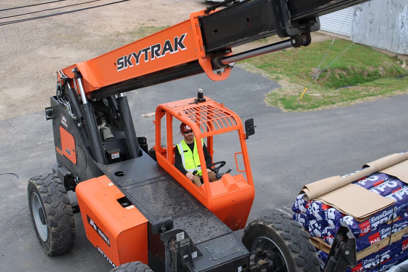 SkyTrak telehandler operator lifting pallets of GAF EverGuard TPO membrane to a rooftop