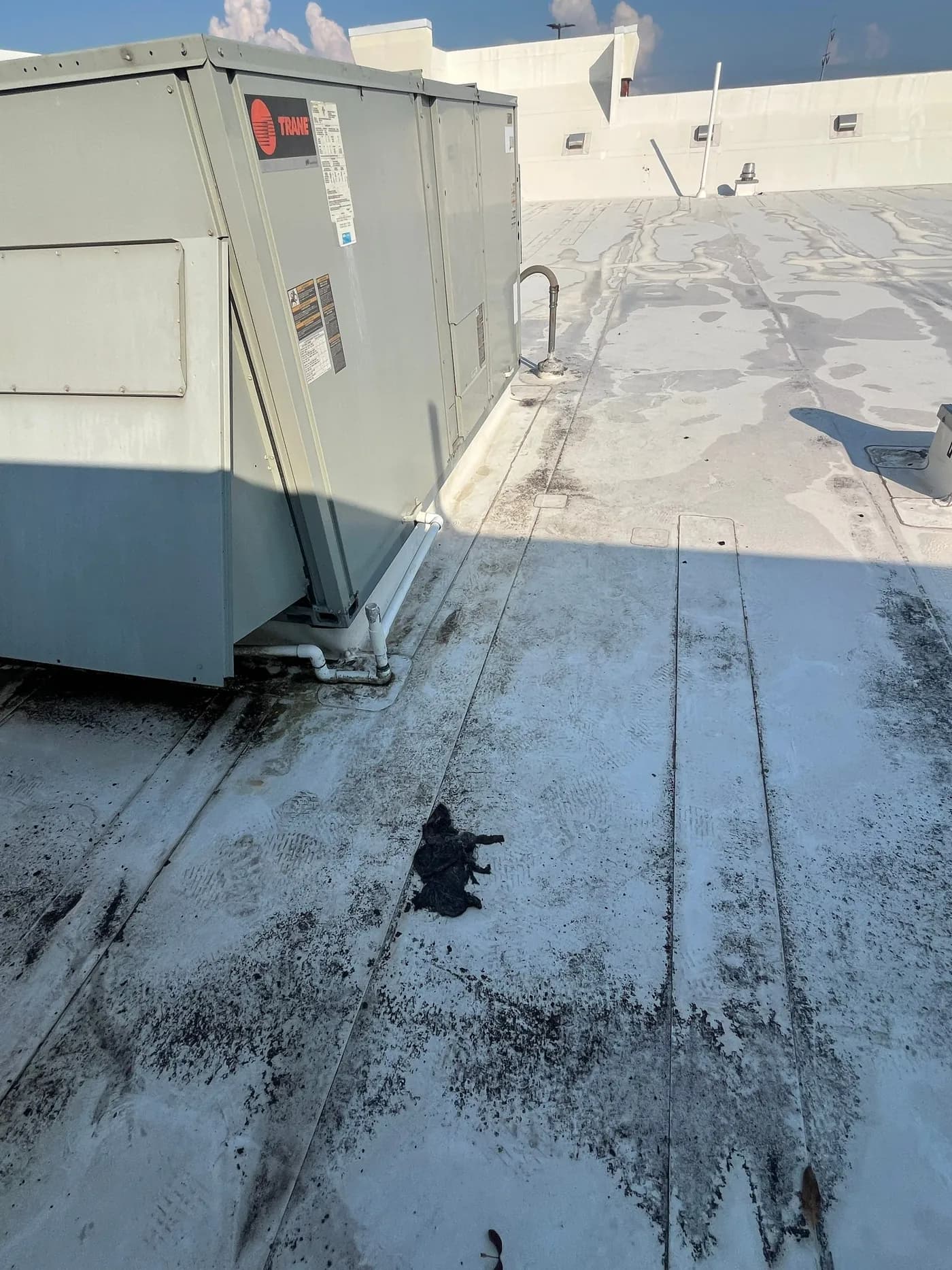 Commercial flat roof in Little Rock before soft-wash, showing tar staining and surface contamination around an HVAC unit