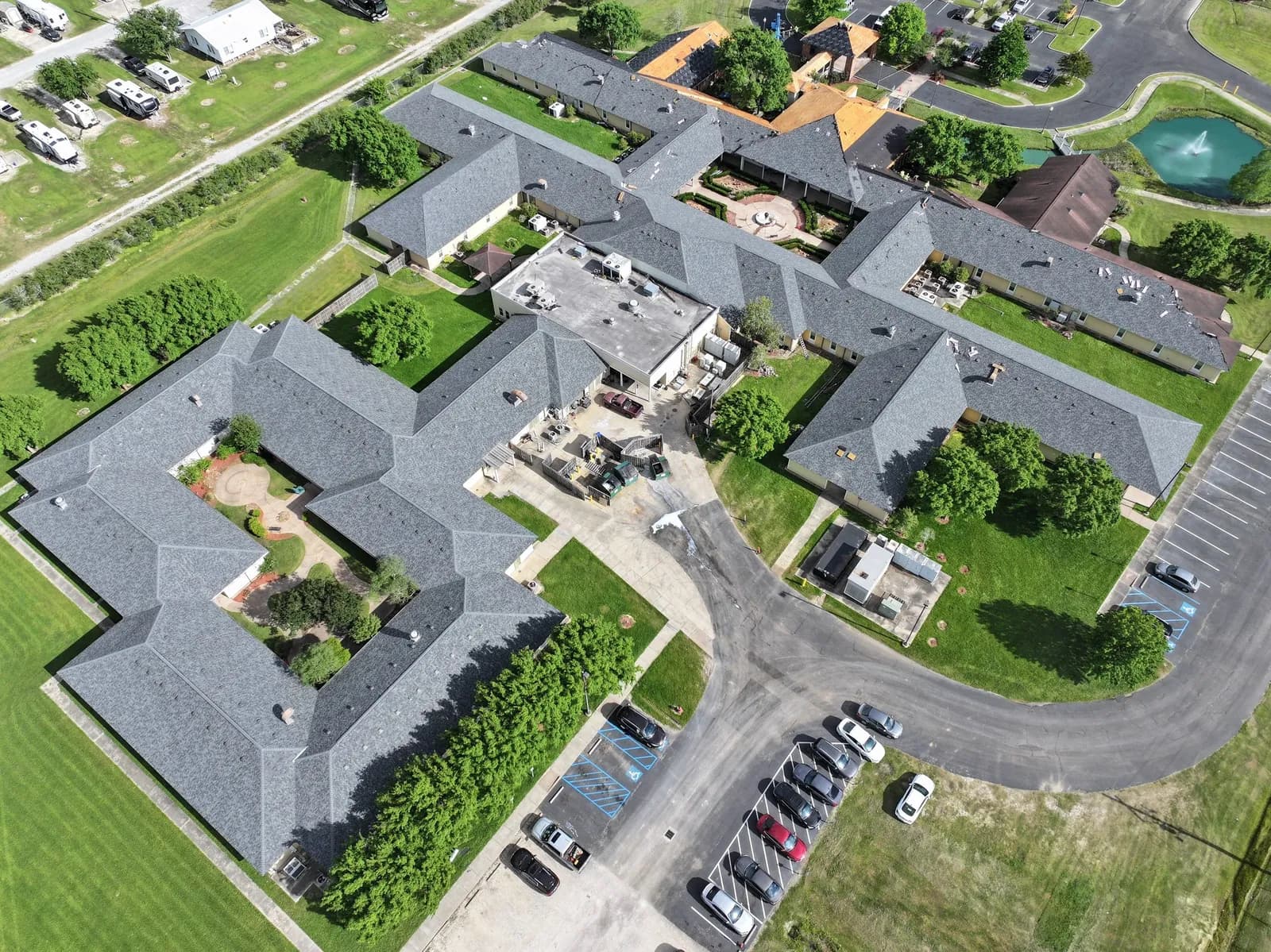 Drone aerial of a multifamily community with new gray shingle roofs and a courtyard