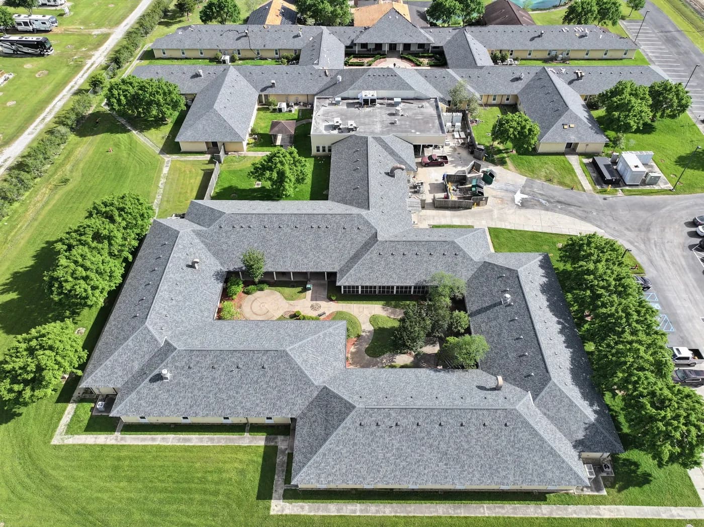 Drone aerial of a multifamily community with new gray shingle roofs and a central courtyard