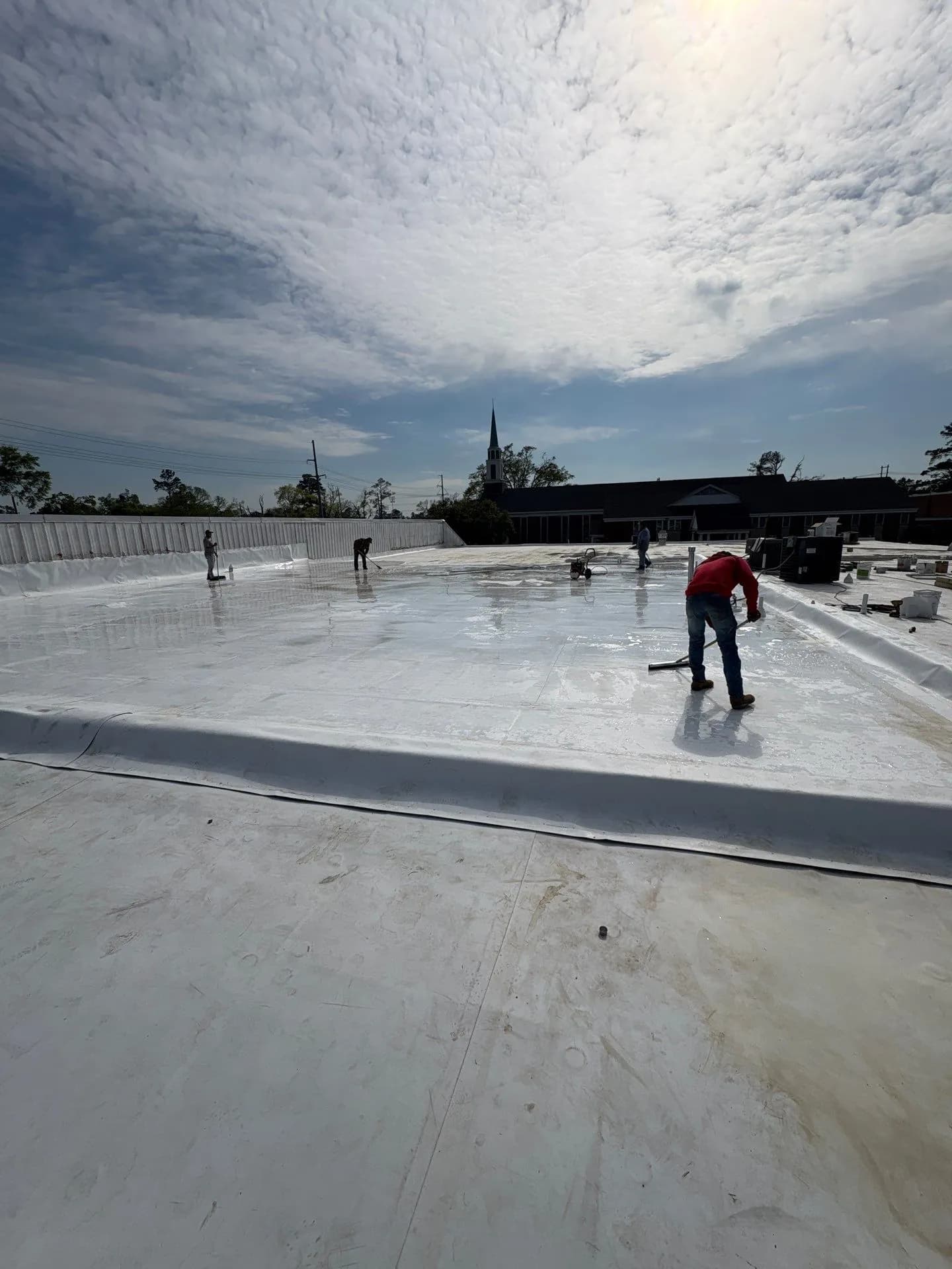 Brown's Roofing crew installing white TPO membrane on a commercial flat roof