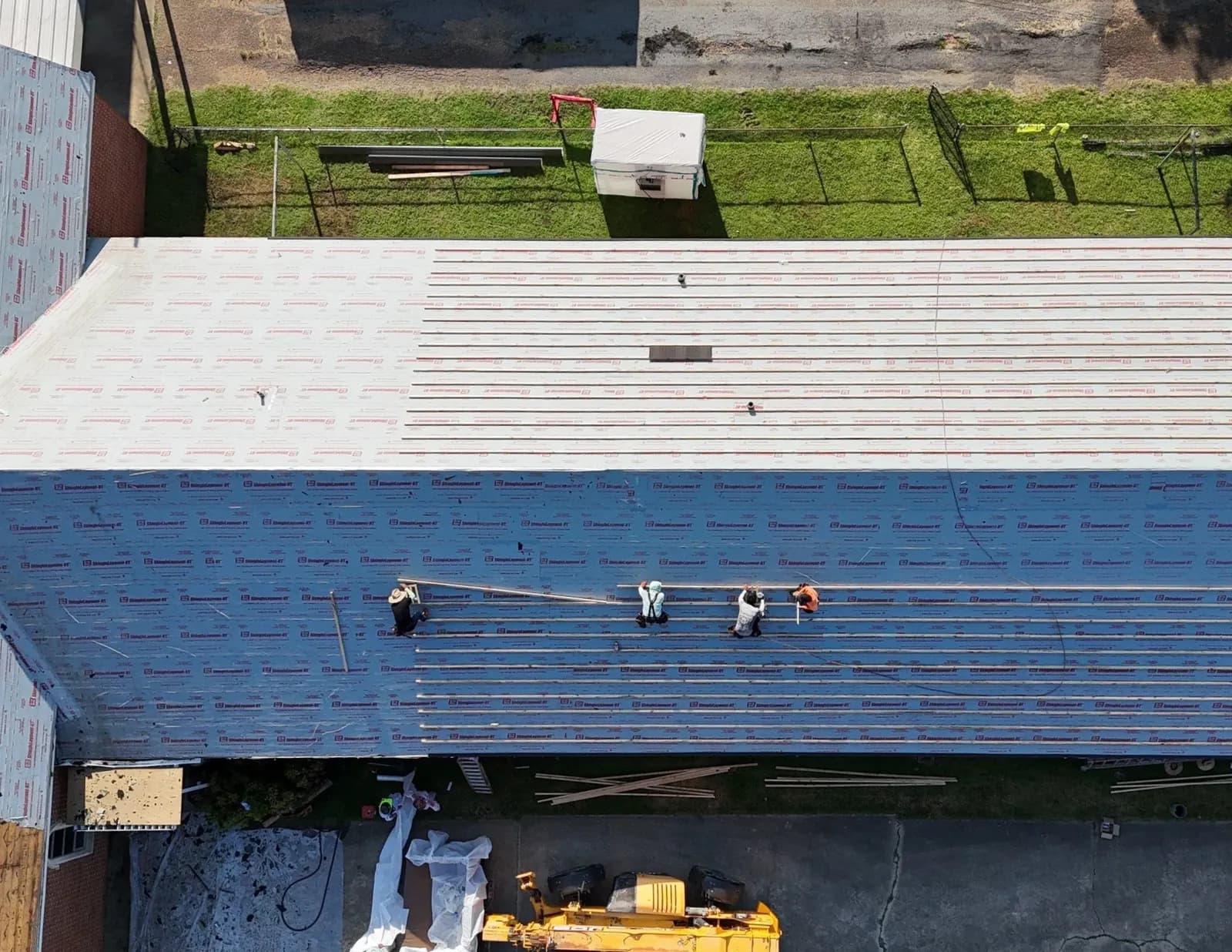 Aerial view of a commercial warehouse reroof in progress with Brown's Roofing crew laying new underlayment
