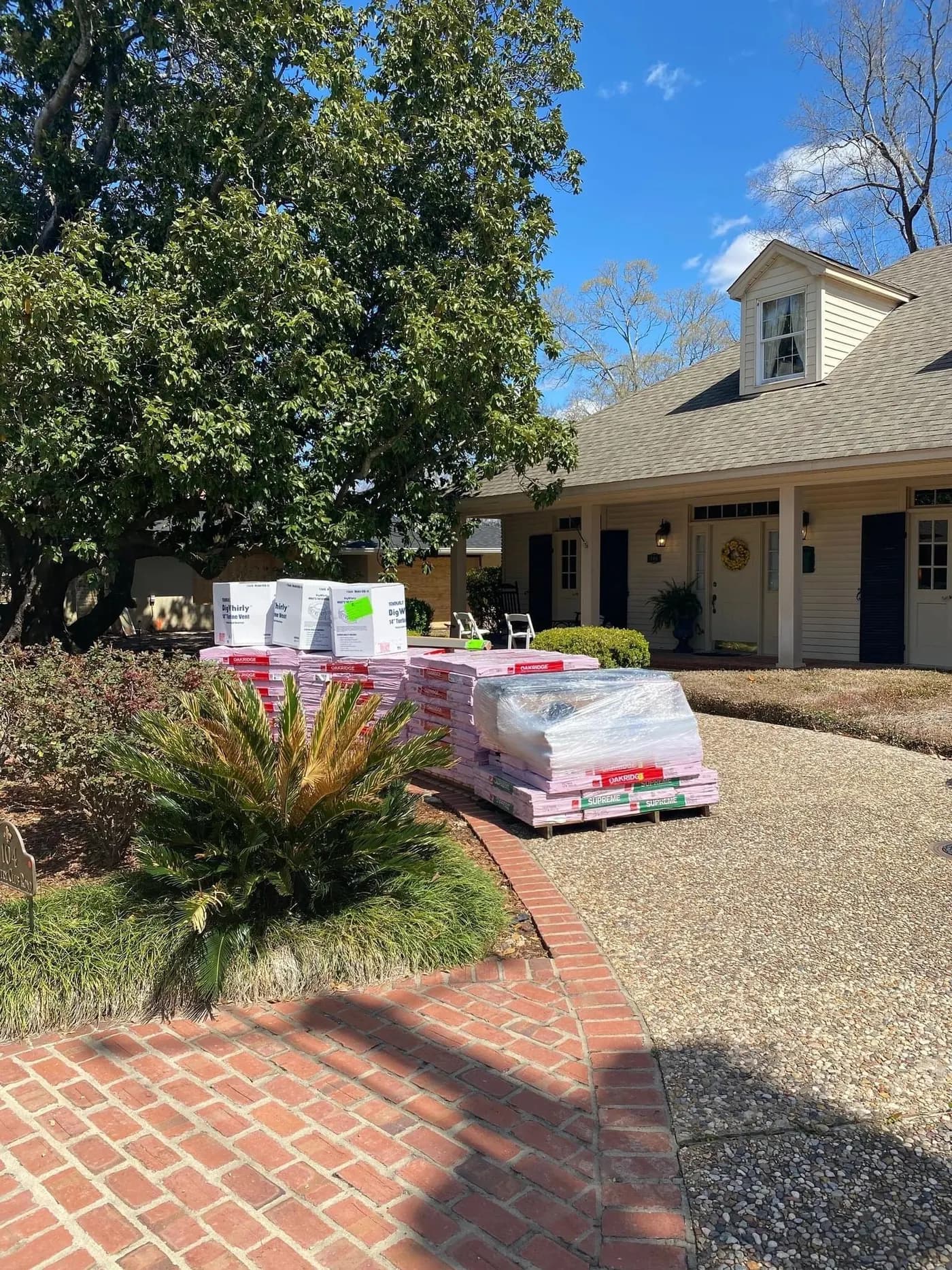 Stacks of new shingle pallets delivered to a driveway for a Brown's Roofing reroof