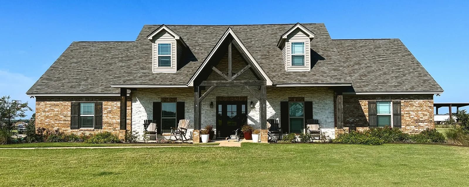Baton Rouge Acadian-style brick home with cedar-truss porch gable and a new dark architectural shingle roof