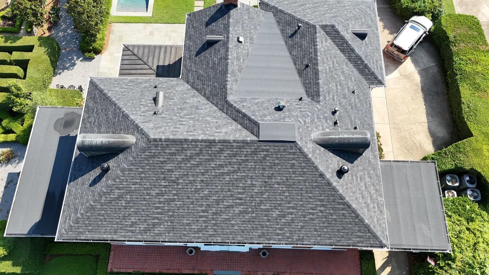 Aerial view of a large Monroe-area home with a sprawling gray architectural shingle roof