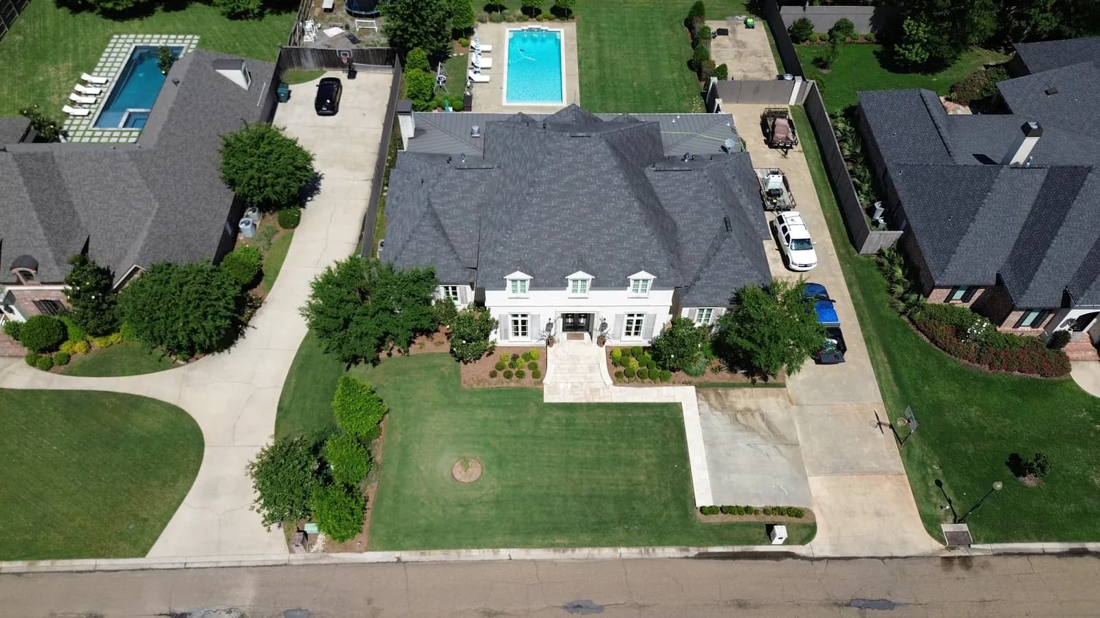 Same Baton Rouge residential estate from the street after soft-wash, with clean dark-gray architectural shingles
