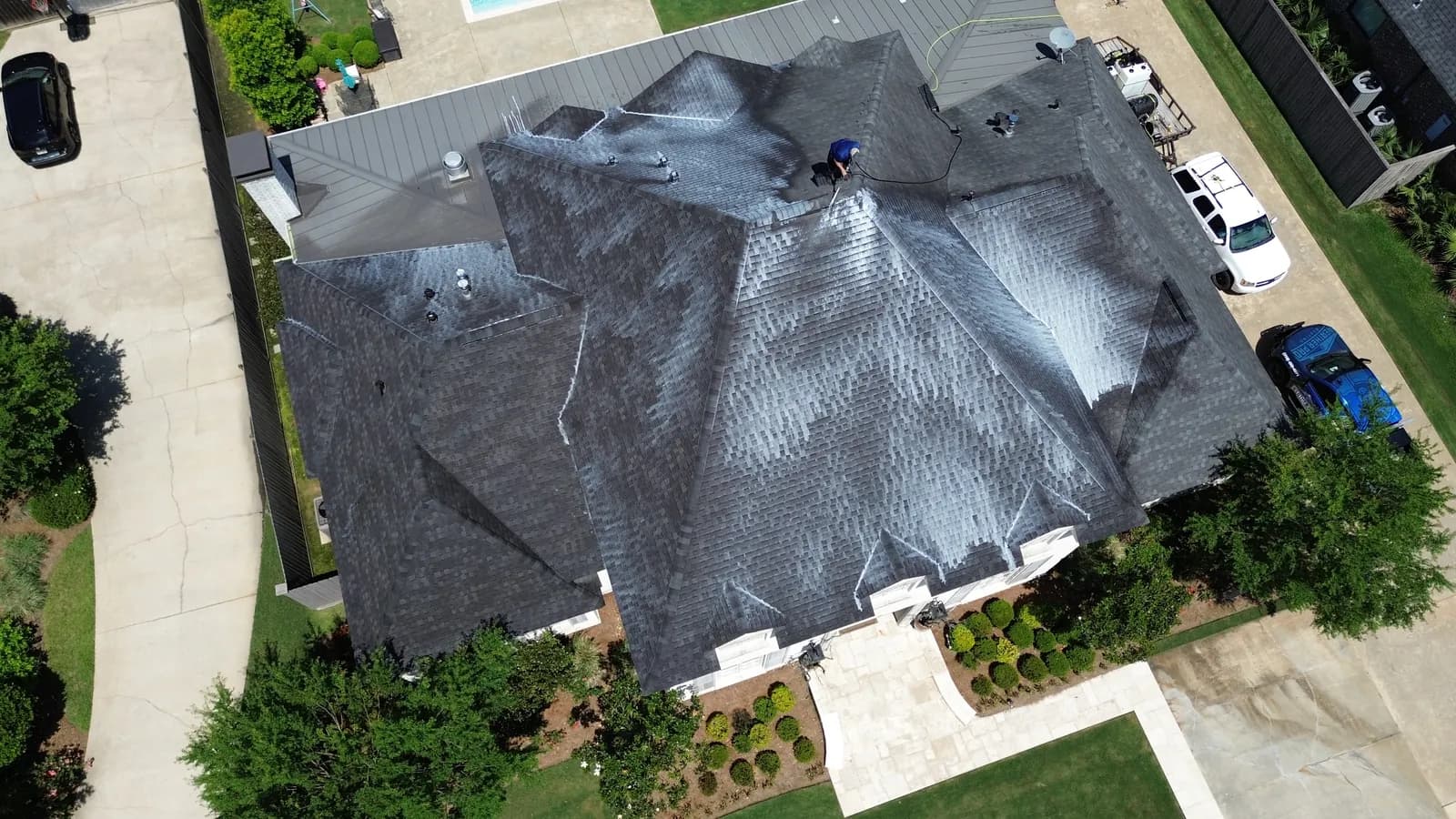 Baton Rouge residential roof mid-soft-wash, with ARMA-spec chemistry visibly streaking down the dark-gray architectural shingles
