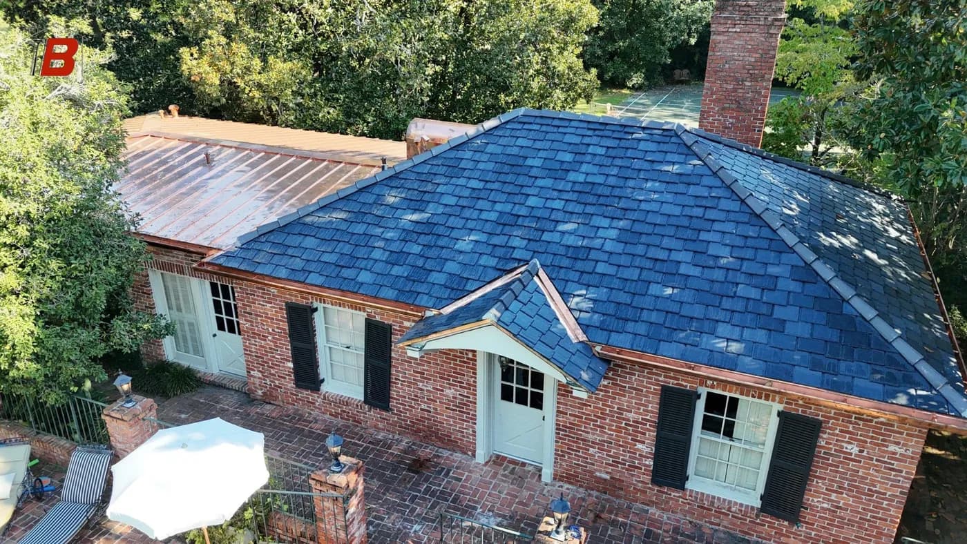 Brick cottage with a synthetic slate main roof and copper standing-seam side wing