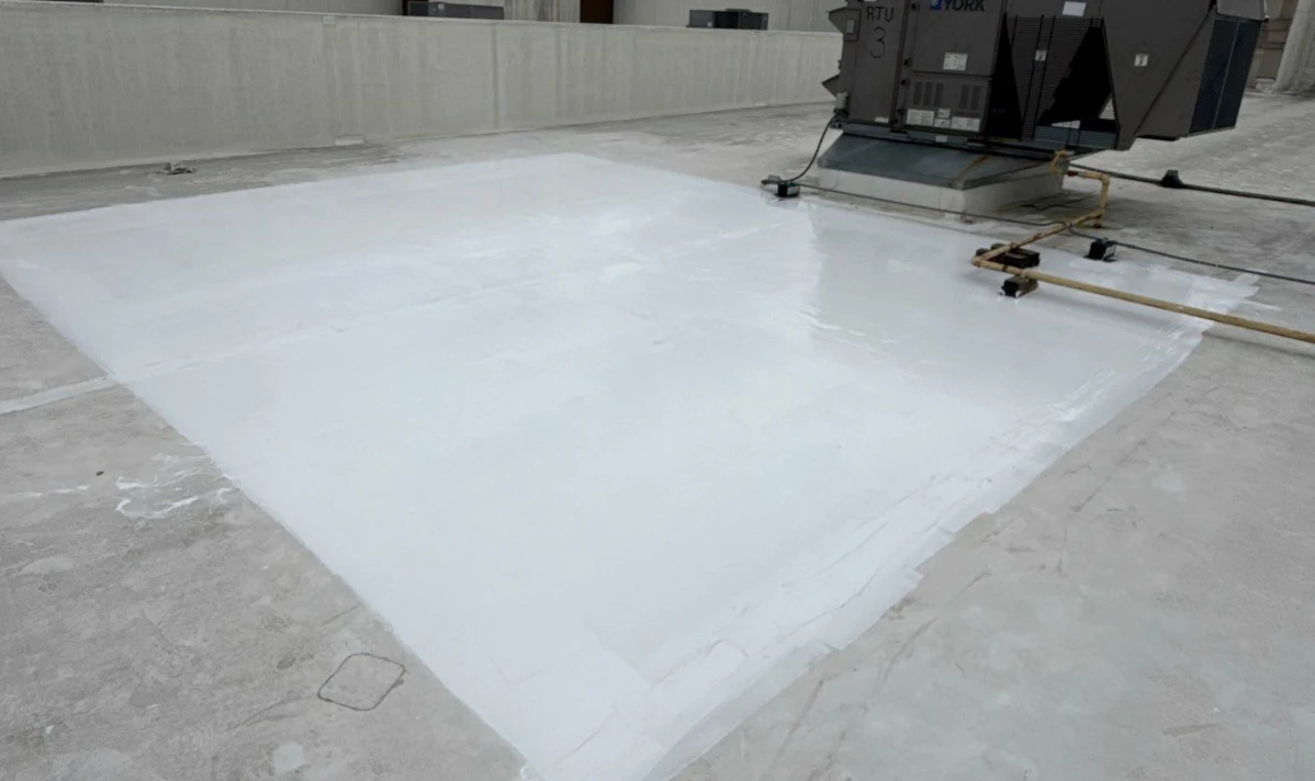 White silicone roof coating freshly applied on a commercial roof restoration around a rooftop HVAC unit