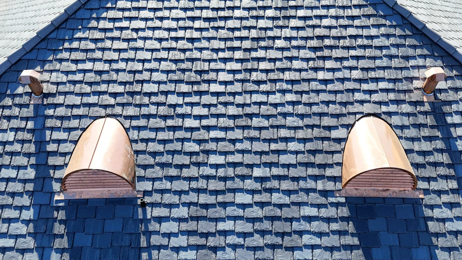 Copper barrel dormers with soldered copper apron flashing set into a blue synthetic slate roof