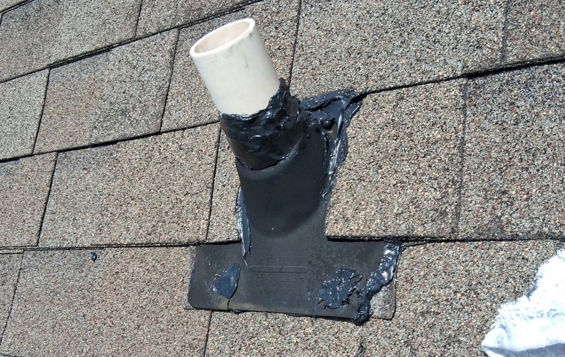 Pipe boot around a plumbing vent on an asphalt shingle roof, patched with roof cement — a common weak point ahead of fall rains