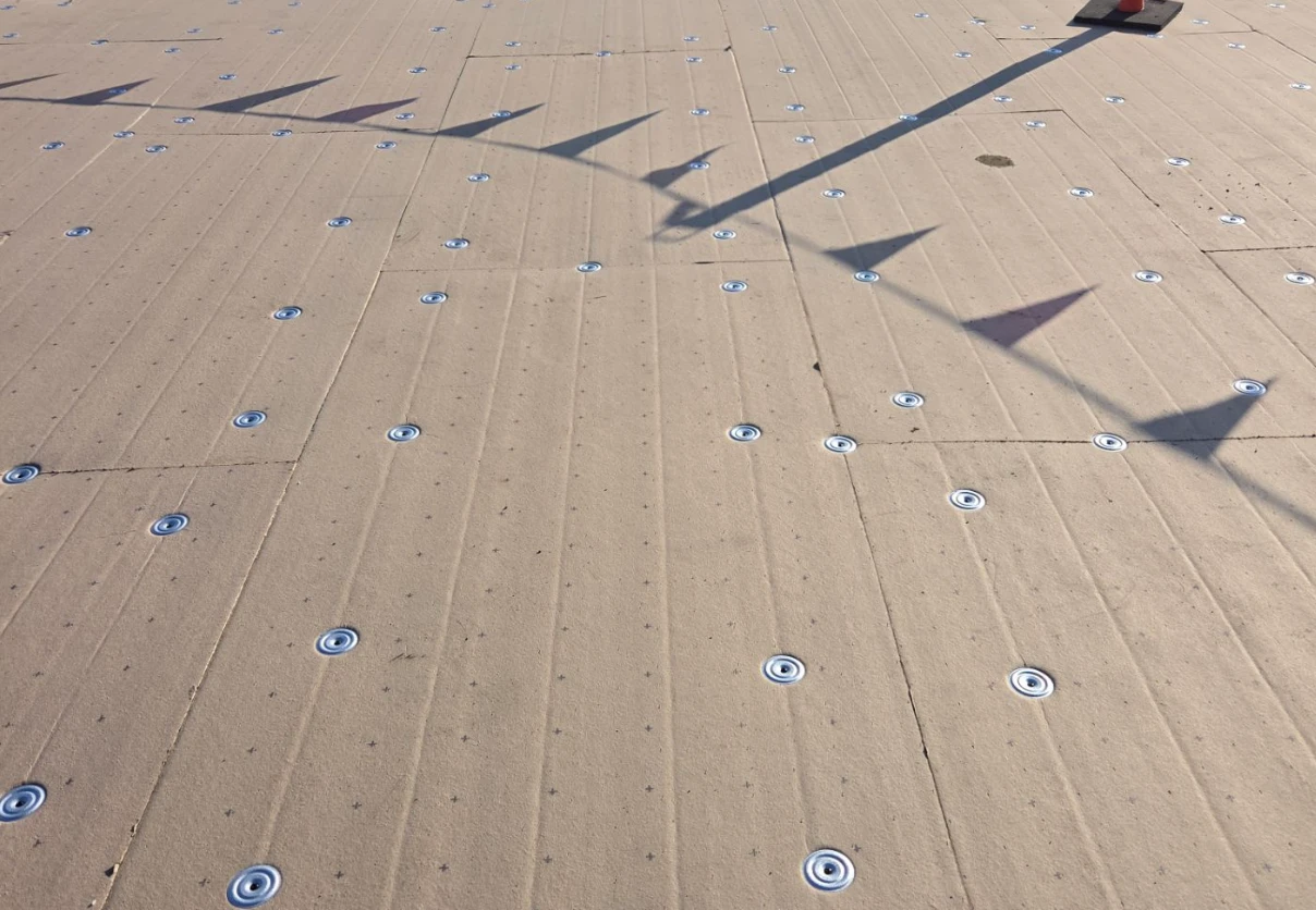 New insulation board mechanically fastened across a clean deck during a commercial roof replacement in Monroe, LA