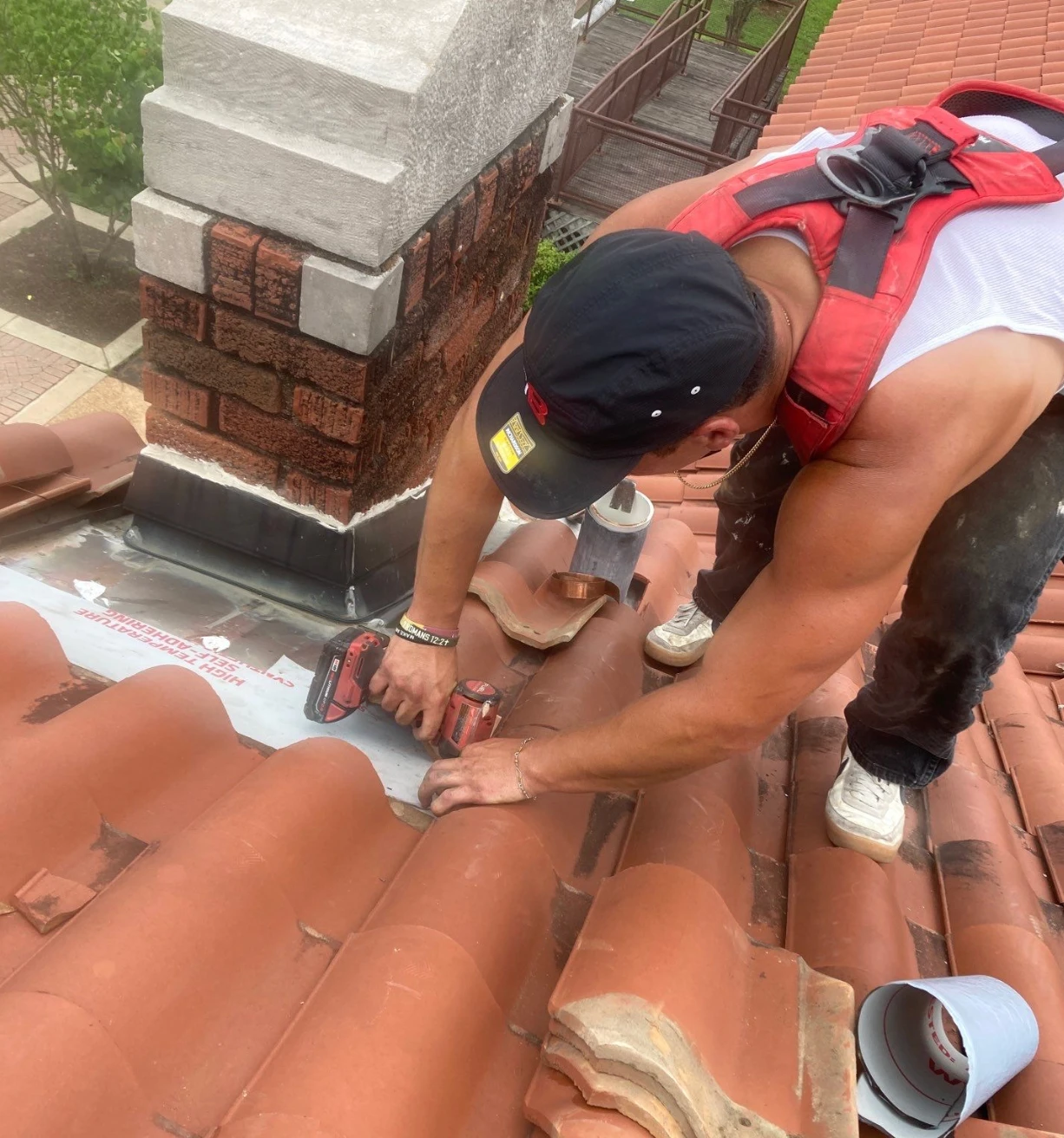 Brown's Roofing technician repairing clay tile and copper flashing at a chimney on the Vivian Railroad Station Museum roof