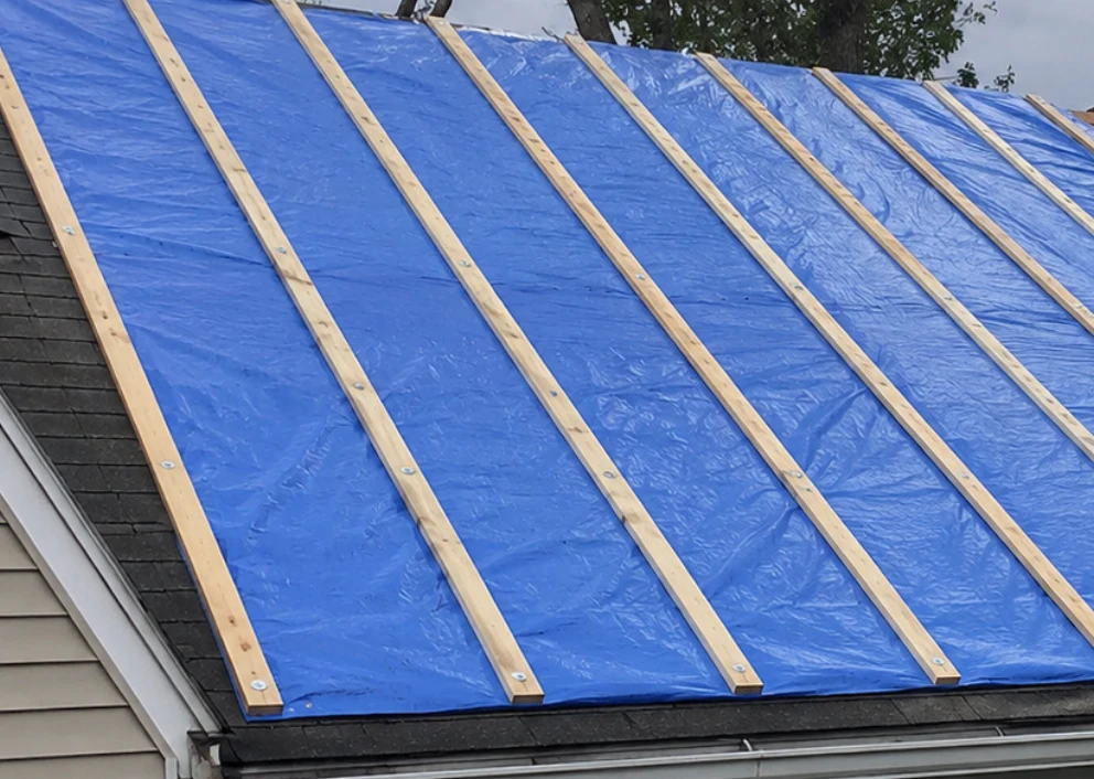 Nail-and-batten emergency roof tarp installed after storm damage in South Louisiana