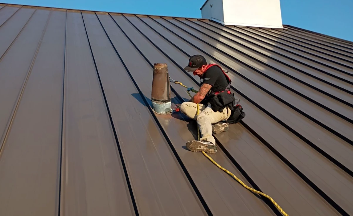 Brown's Roofing crew member working on a standing-seam metal roof