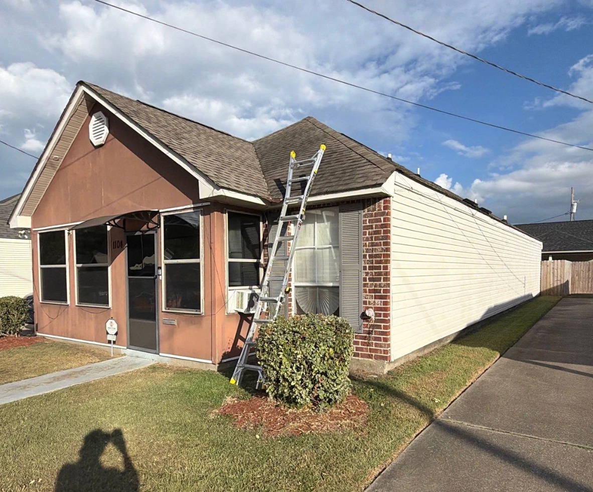 Ladder set against an asphalt shingle roof for a pre-storm roof inspection on a Baton Rouge home