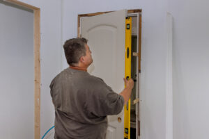 An employee leveling the interior doors of a new house during the installation of the doors is checking whether the correct installation door is being installed